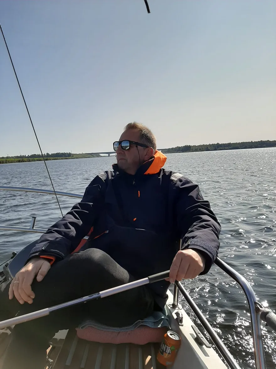 René aan het roer van een zeilboot op open water